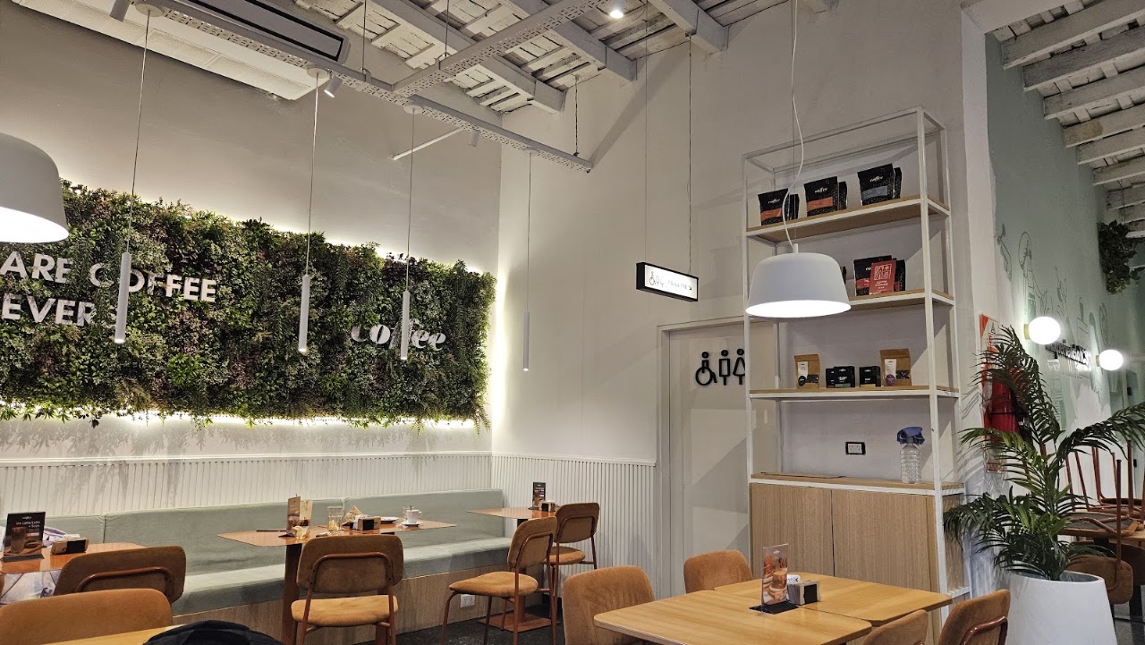 Interior de The Coffee Store Caballito, con pared verde y mesas de madera